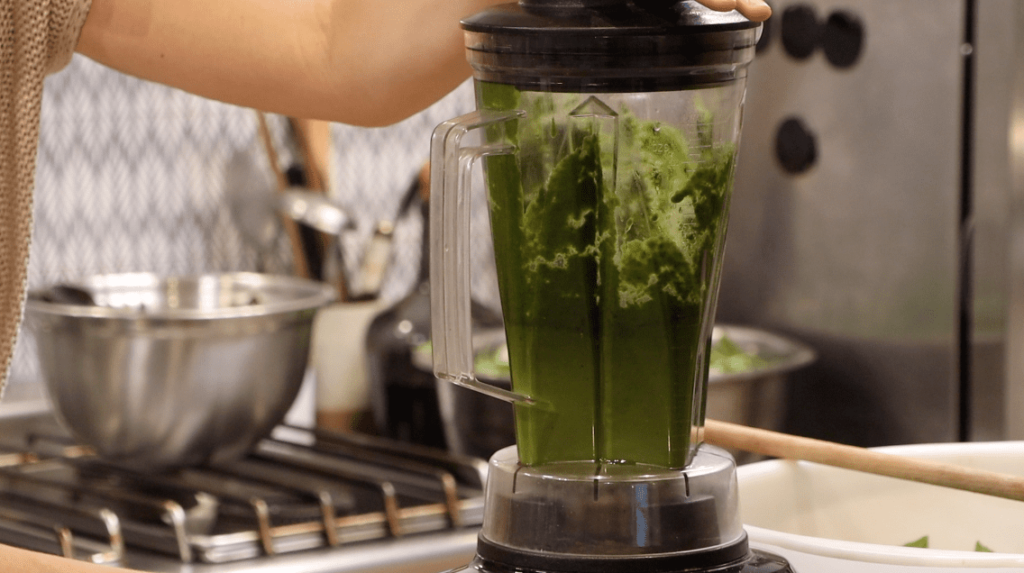 high-speed blender in professional kitchen filled with green paste