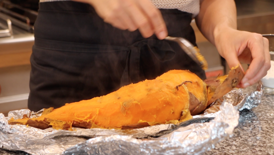 big roasted sweet potato being peeled with a spoon