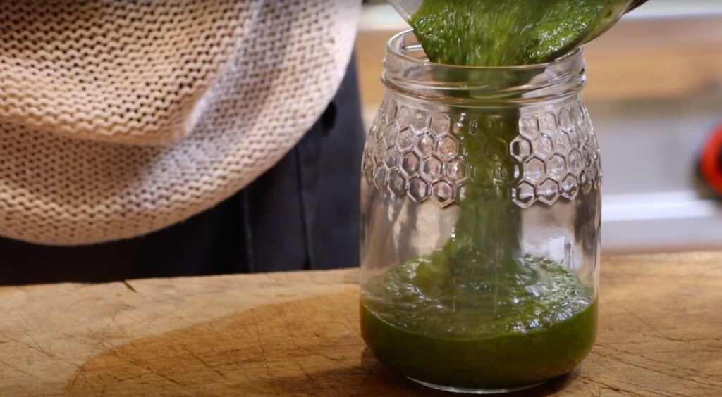 green paste being poured into glass jar