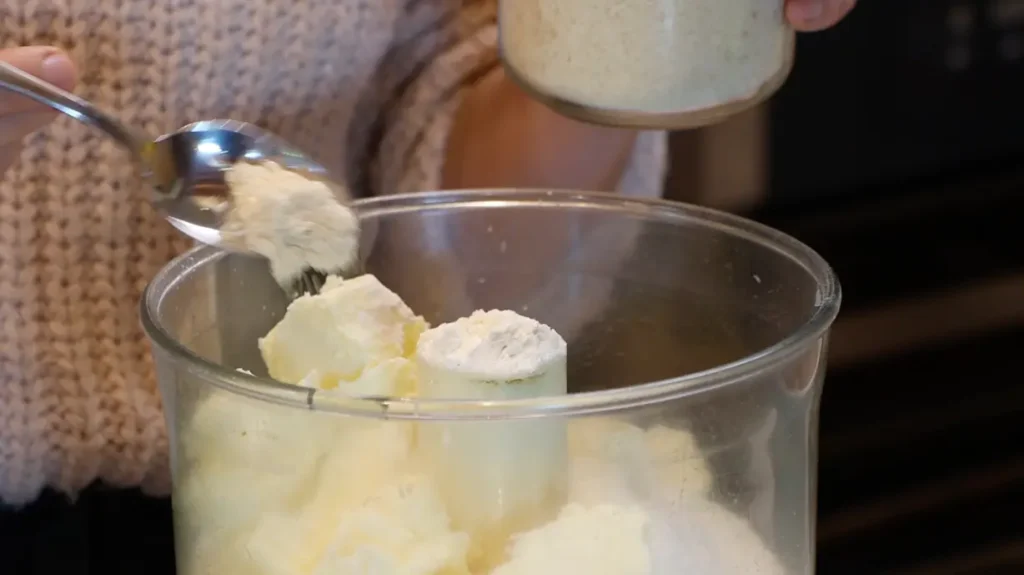 open food processor with white powder and butter pieces