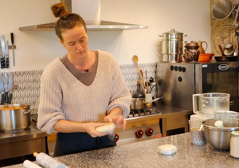 woman wrapping disk shaped piece of dough in transparent plastic