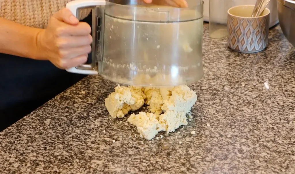 crumbly dough on black and white stone surface, food processor upside down