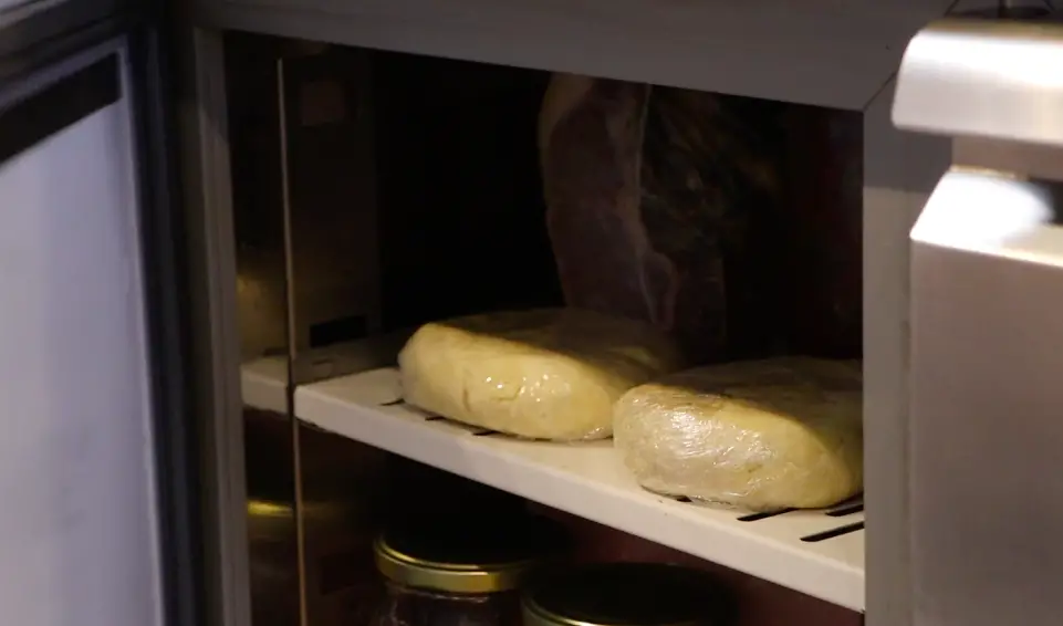 two dough pieces in transparent plastic inside a fridge