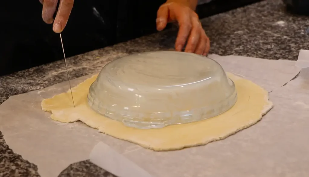 upside down pie dish on dough sheet, knife cutting around in circle