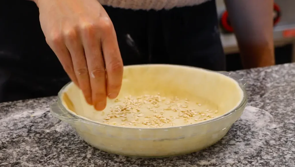 grain dropping from hand into raw pie crust