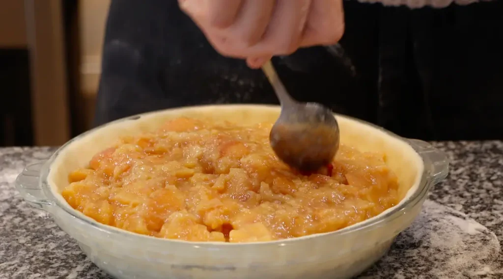 pie base with fruit filling being spread with spoon