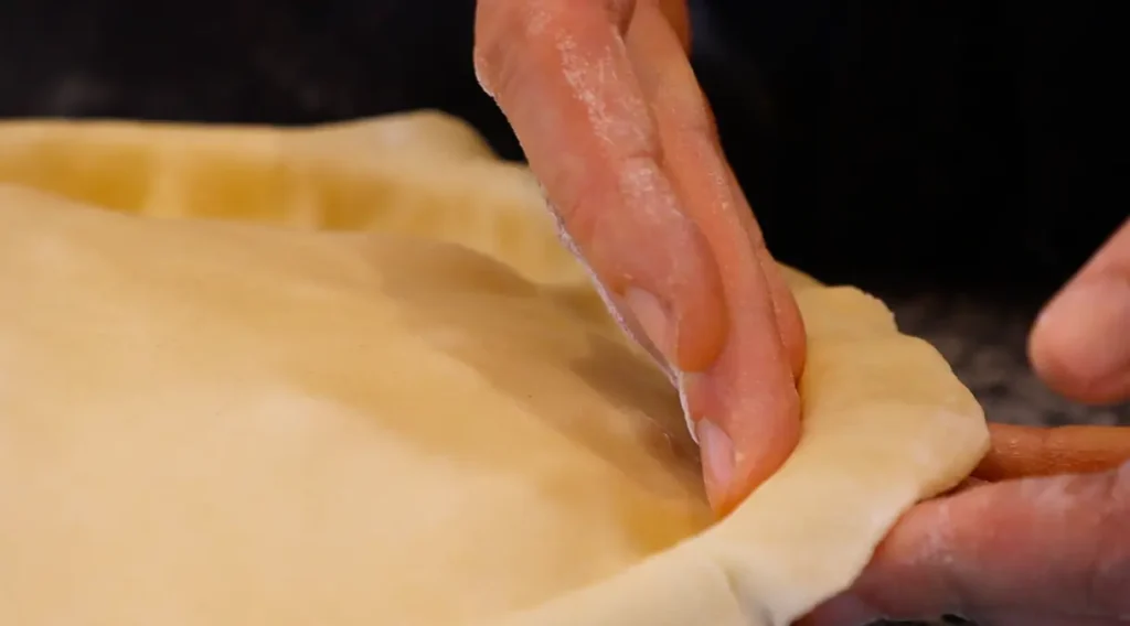 hand pressing dough on edge of pie dish