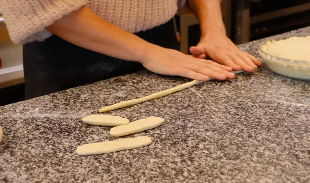 two hands rolling dough into thin rope