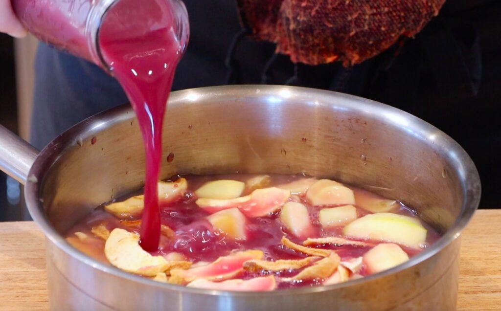 silver pot with fruit pieces, purple juice running into it