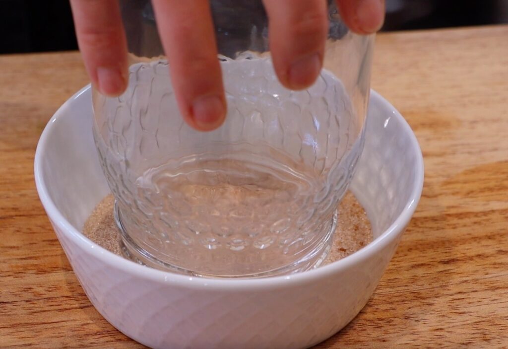 glass jar upside down in white bowl with sand-like substance, three finger holding