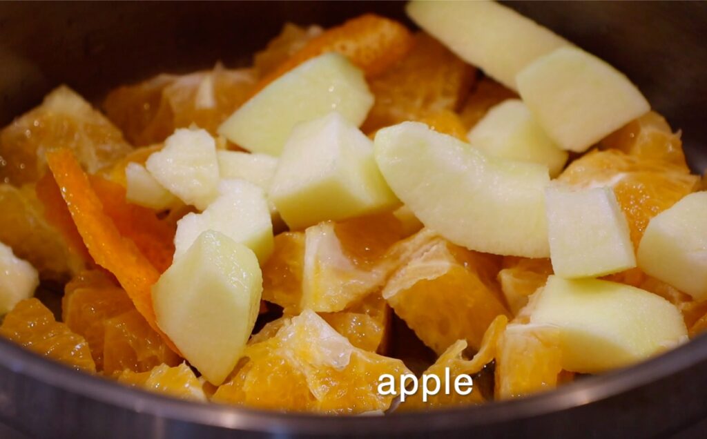 apple and orange pieces in pot, writing