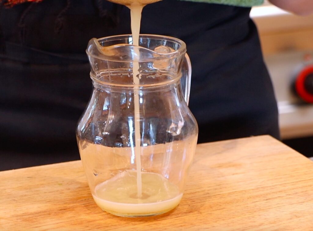 liquid running through metal sieve into glass jug