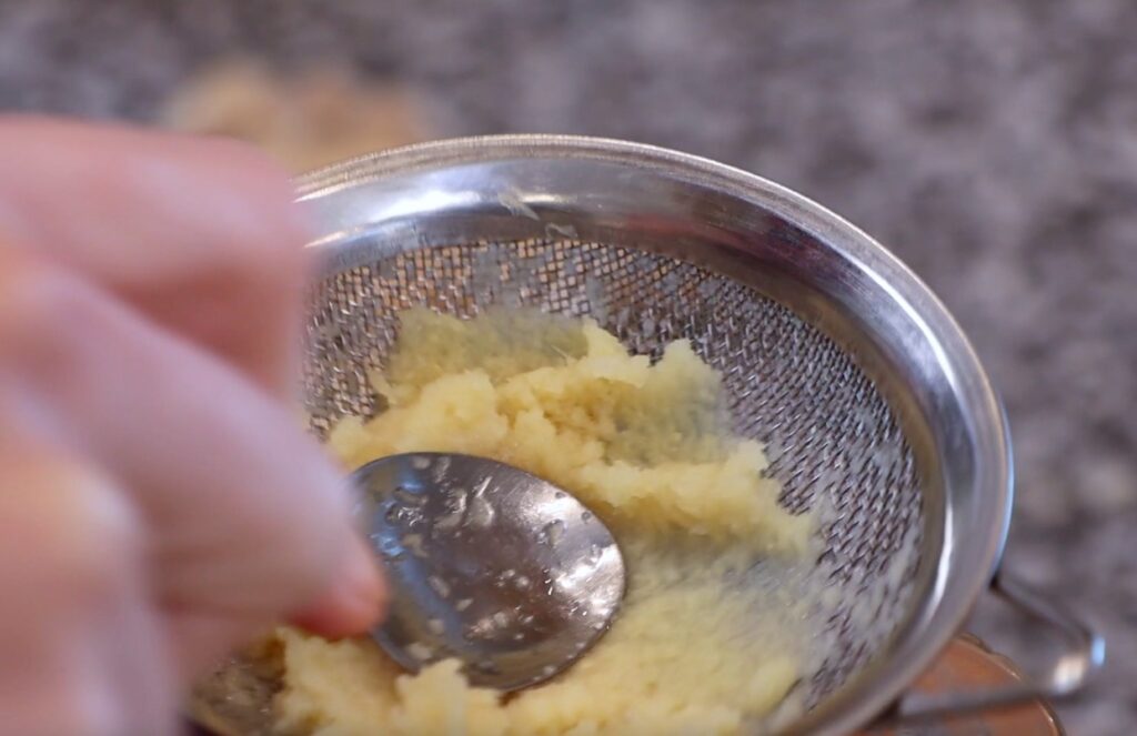 ginger pulp in metal sieve and metal spoon