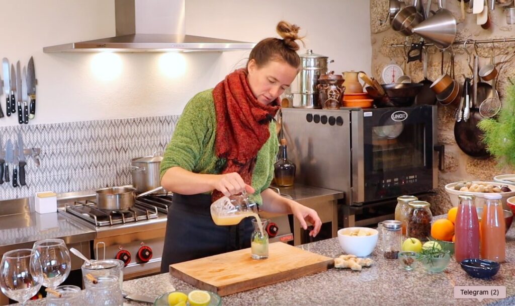 woman pouring liquid into small glass bottle containing green leaves