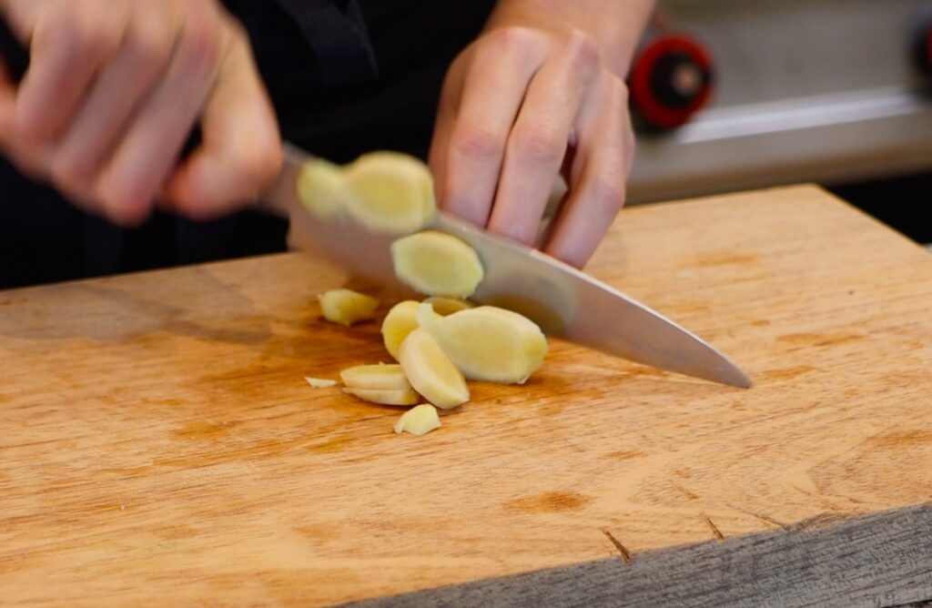 ginger being sliced on wooden board