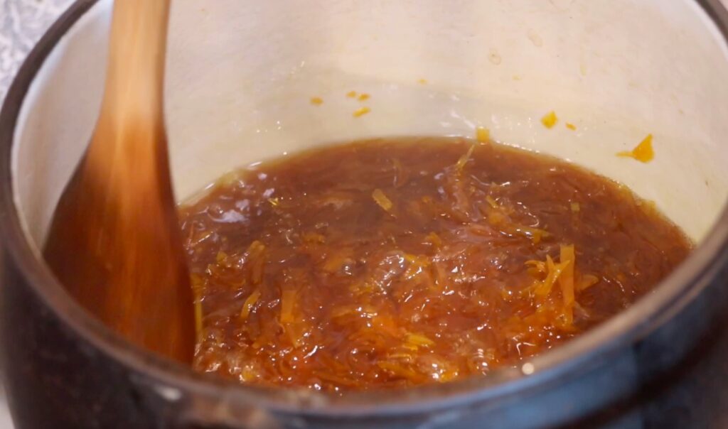 pot with dark orange golden liquid and small pieces, wooden spoon