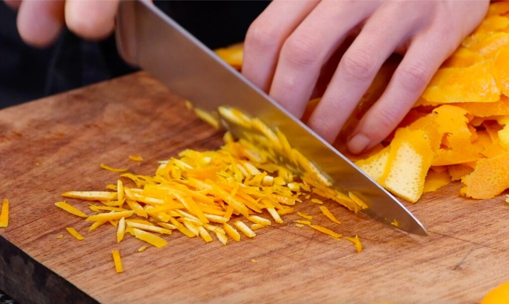 cutting orange peels into thin slivers with big knife