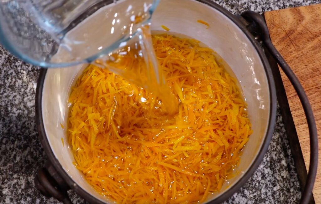 pot with orange peels from above, water pouring from glass jug