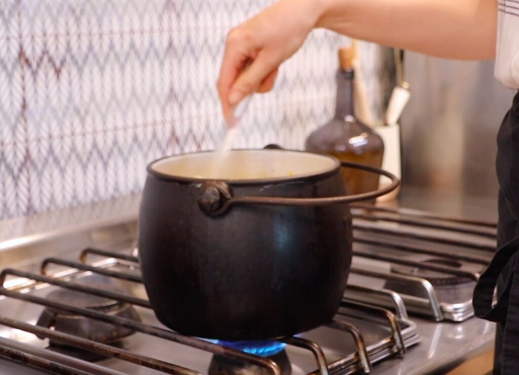 black pot on stove, hand stirring