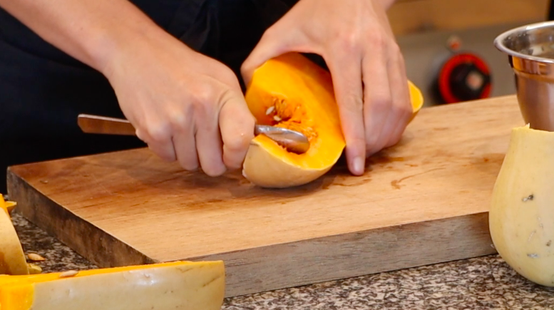 light orange, cut pumpkin, metal spoon scooping seeds