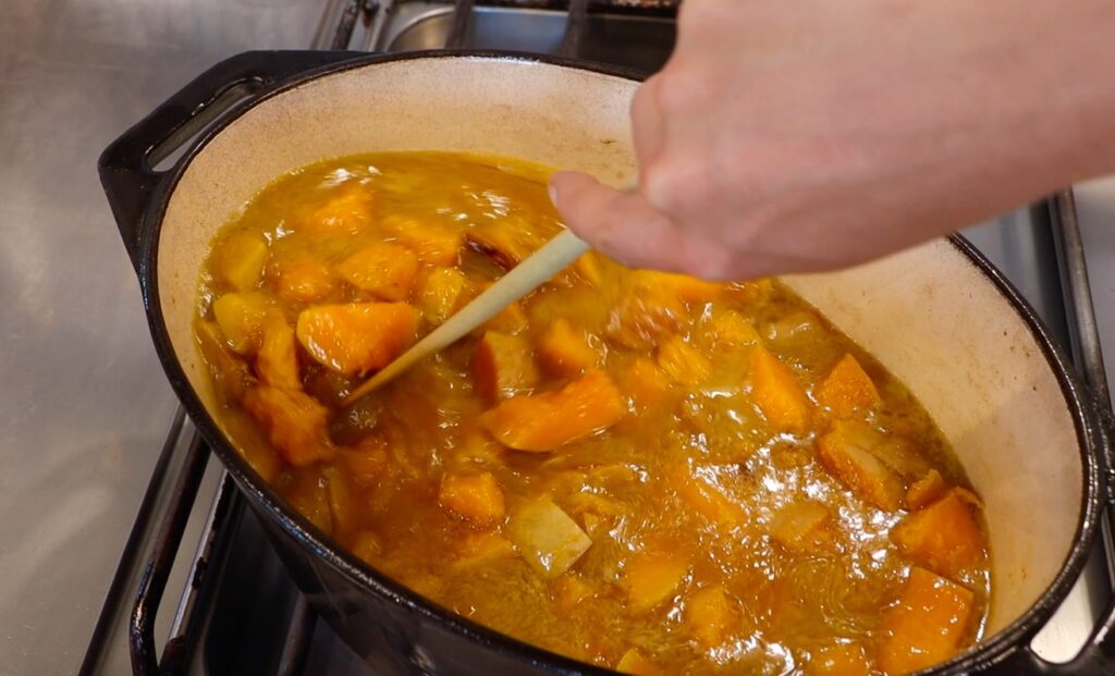 pot with pumpkin pieces in water, stirring with plastic spoon