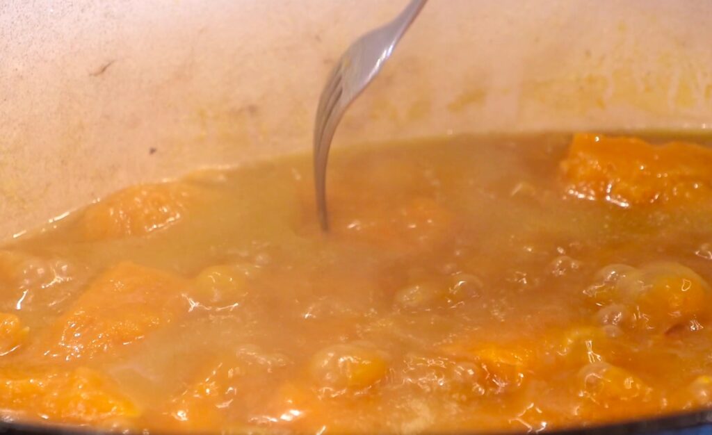 close-up simmering soup and metal fork hovering above