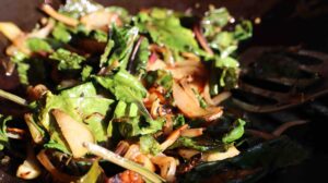 close up, green beet leaves, onion, beet slices in pan and sunshine