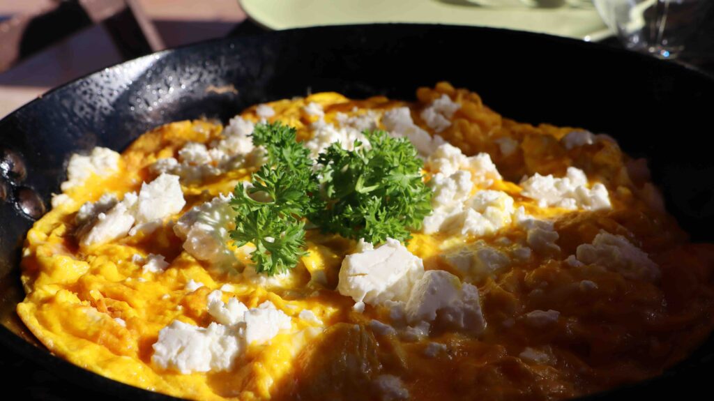 dark yellow omelet, feta crumbs, green, curly decorative leaf in pan