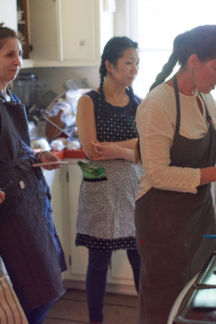 Cooking workshop participants preparing food together in a rustic kitchen
